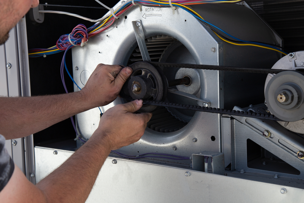 An HVAC technician working on the motor, a typical process when you replace your HVAC unit